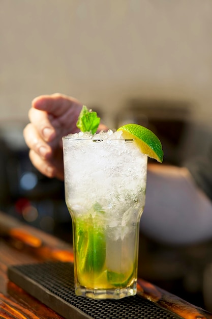 Barkeeper dekoriert Cocktail-Mojito mit Minze und Limette