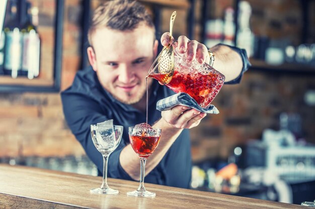 Foto barkeeper, der cocktail-alkoholgetränke in manhattan gießt barkeeper in einem pub oder restaurant, der einen cocktail-getränk zubereitet