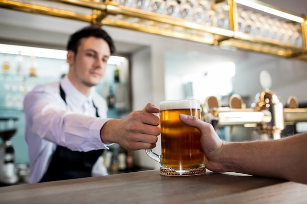 Barkeeper, der dem Kunden Bier serviert