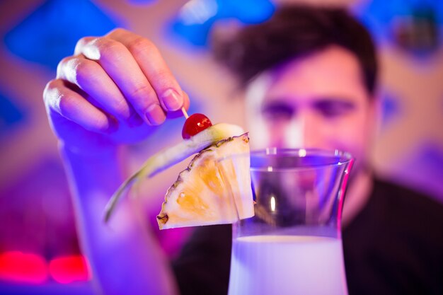 Barkeeper, der Früchte auf Cocktailglas hält