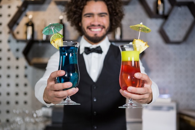 Barkeeper, der zwei Glas Cocktail in der Bartheke hält