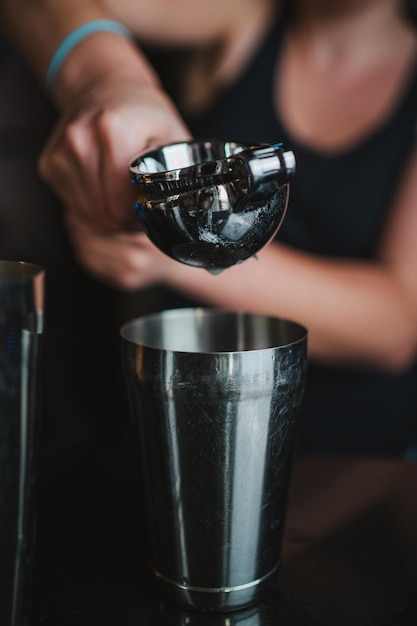 Barkeeper exprimiendo un limón con un exprimidor de mano para preparar un cóctel de pisco sour