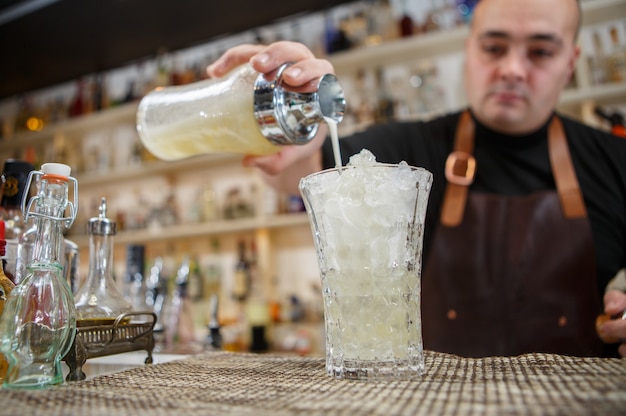 Barkeeper gießt Cocktail in Glas an der Bar