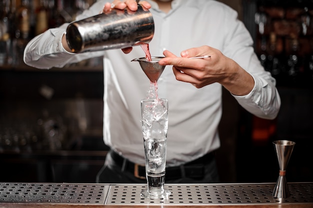 Foto barkeeper gießt ein alkoholisches getränk aus dem stahlschüttler