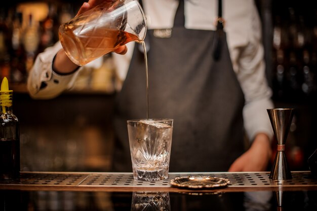 Barkeeper gießt ein frisches alkoholisches Getränk aus einem Mischglas