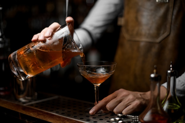 Barkeeper gießt einen Alkoholcocktail aus Sieb