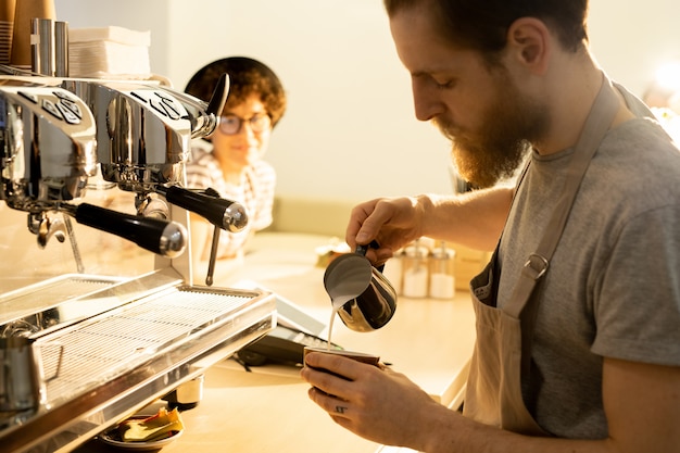 Barkeeper gießt Milch in Kaffee