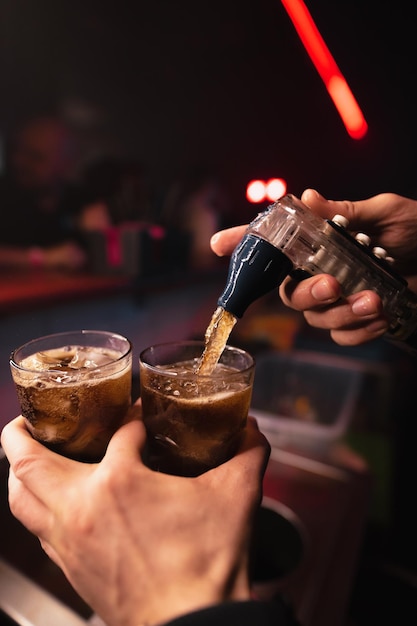 Barkeeper gießt Soda in alkoholische Cocktails in einem Nachtclub