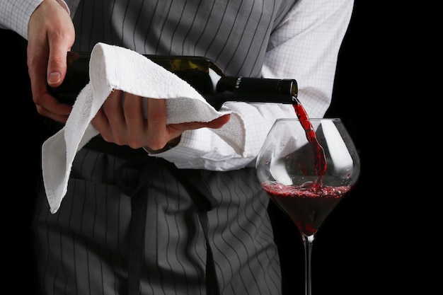 Barkeeper gießt Wein in Glas auf dunklem Hintergrund