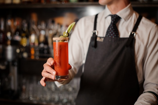 Barkeeper hält einen Bloody Mary Cocktail mit Oliven und Sellerie