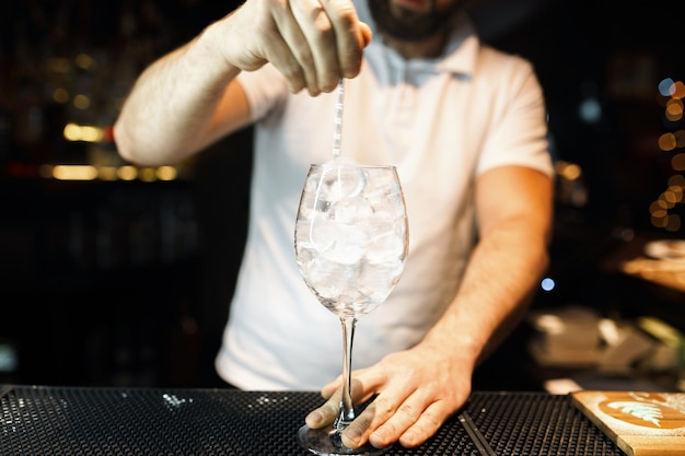 Barkeeper im weißen T-Shirt an der Bar oder in einem Nachtclub und macht einen alkoholischen Cocktail. Lebensstil