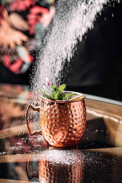 Barkeeper macht Cocktail in Kupferbecher mit Zucker