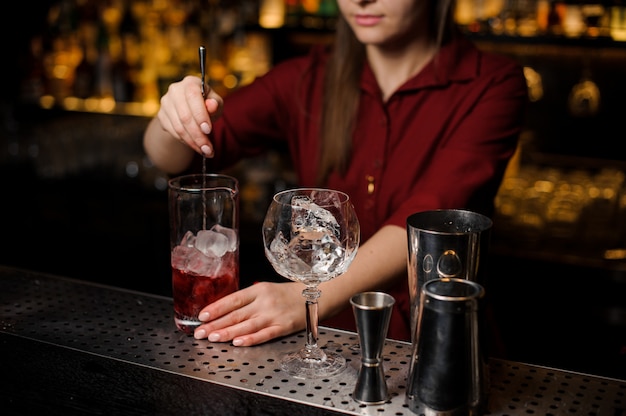 Barkeeper-Mädchen, das einen hellroten Cocktail rührt
