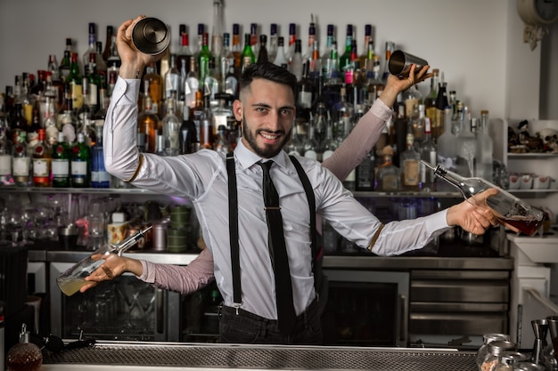 Barkeeper mit Shakern und Flaschen im Pub