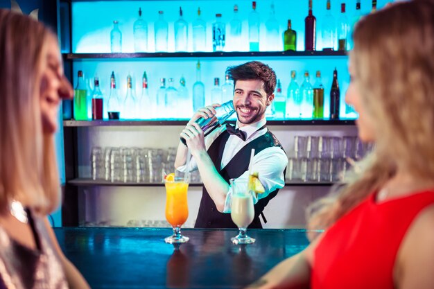 Barkeeper preparando coquetel para clientes do sexo feminino