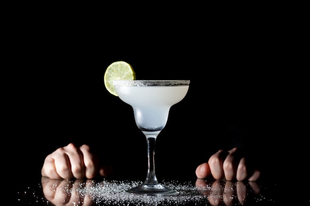 Barkeeper serviert klassische Margarita mit Limette auf schwarzem Hintergrund