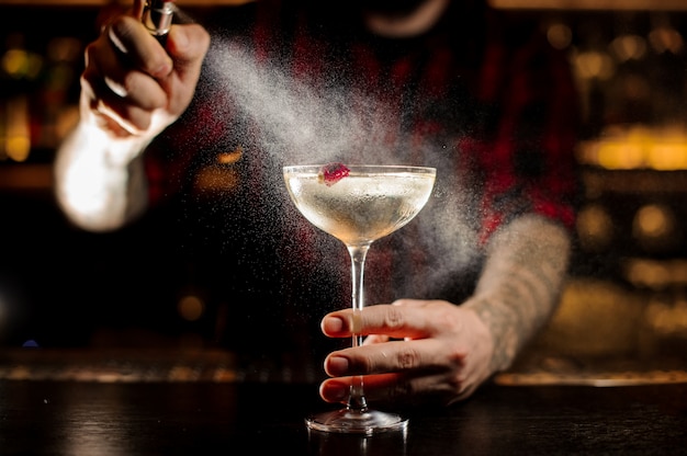 Barkeeper streut bitter auf das elegante Cocktailglas