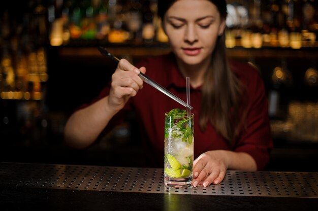 Barmaid i adiciona ao cocktail de álcool mojito cocktail tuba