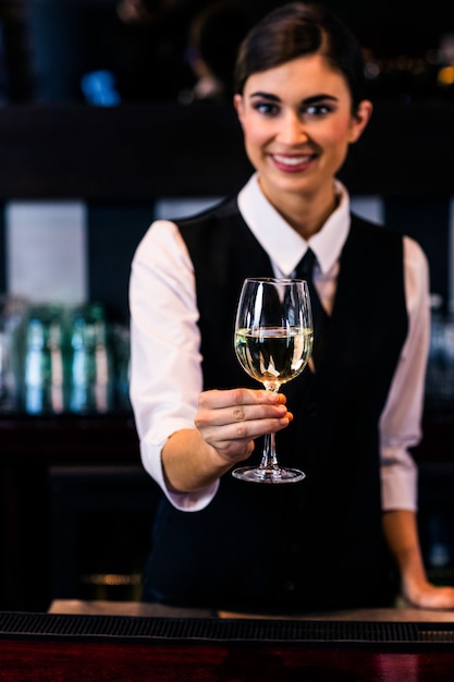 Barmaid sirviendo una copa de vino en un bar