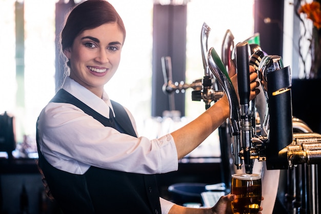 Barmaid sirviendo una pinta en un bar