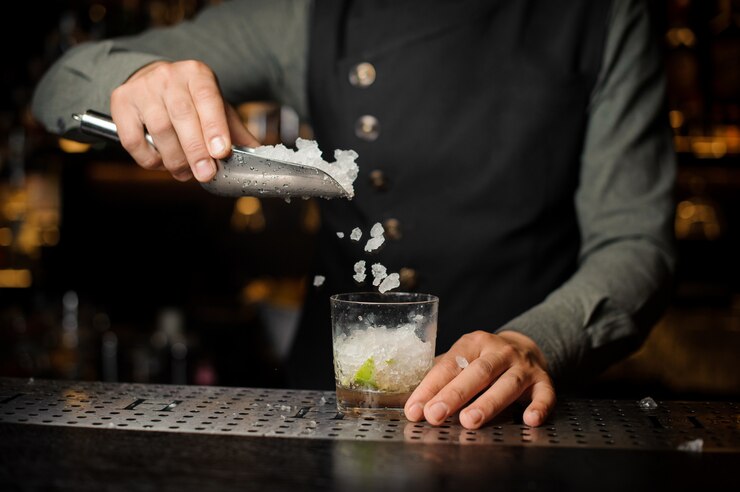 Barman adicionando cubos de gelo no copo de coquetel. Processo de fabricação de Caipirinha