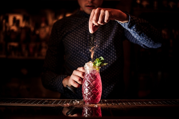 Barman adicionando especiarias para o cocktail de verão mojito de morango fresco e doce