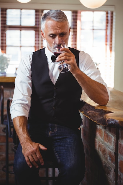 Barman, bebendo vinho no balcão de bar