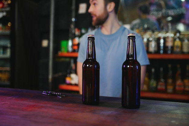 Barman botella de cerveza Vaso vacío cercano en el mostrador de madera en el interior del pub espacio libre recortado