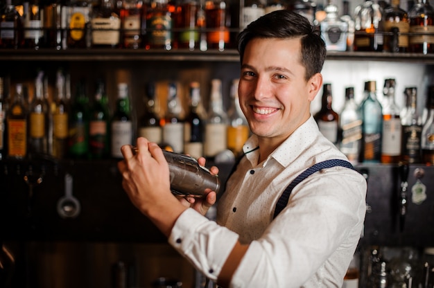 Barman en camisa está haciendo alcohol cóctel sin rostro de cerca