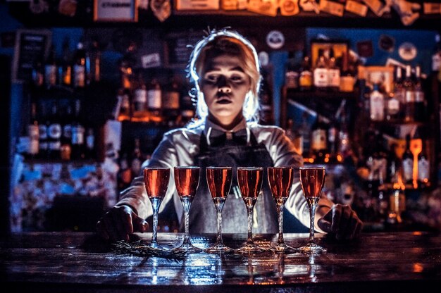 Barman charmosa dando os últimos retoques em uma bebida no balcão do bar