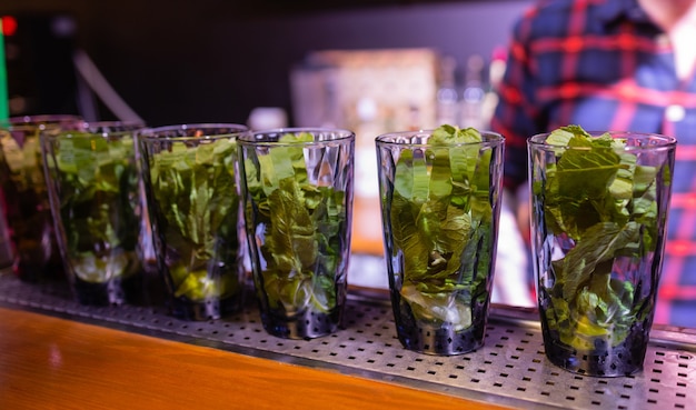 Barman colocando limão no copo. limão amassado para fazer um coquetel. barman segurando o copo.