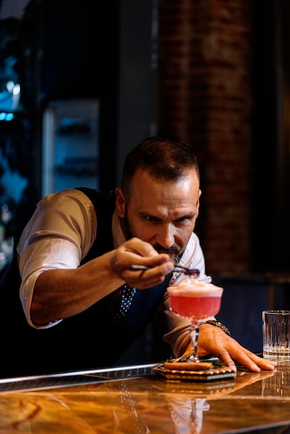 Barman concentrado haciendo bebidas en el mostrador