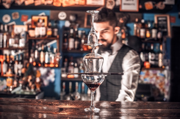 Barman confiante servindo bebida alcoólica fresca nos copos no bar