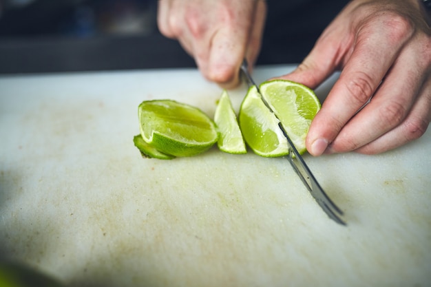 El barman corta un limón en una tabla de cortar