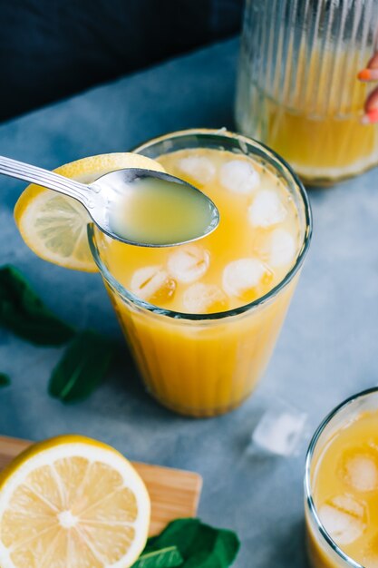 Barman cozinhando limonada fresca com colher em um copo com gelo