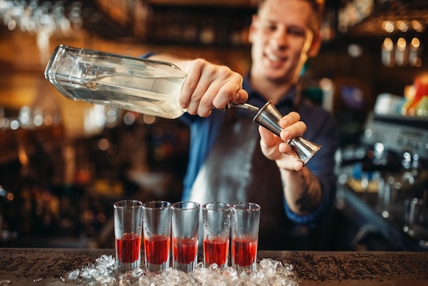 Barman de avental preparando um coquetel alcoólico