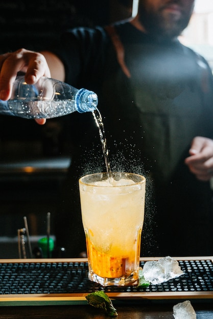 Barman de mão fazer coquetel. cocktail tem folhas de laranja e hortelã.