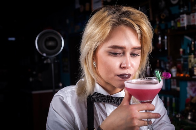 Barman de mulher encantadora dá os toques finais em uma bebida enquanto está perto do balcão do bar no bar