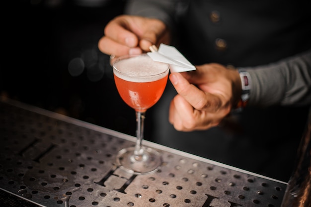 Barman decorando una copa de cóctel con un avión volando de papel