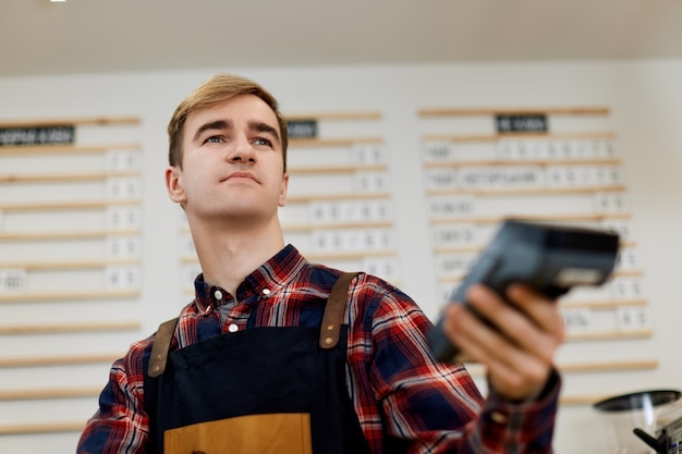 Barman en delantal usando tecnología nfs para procesar y adquirir pagos con tarjeta de crédito