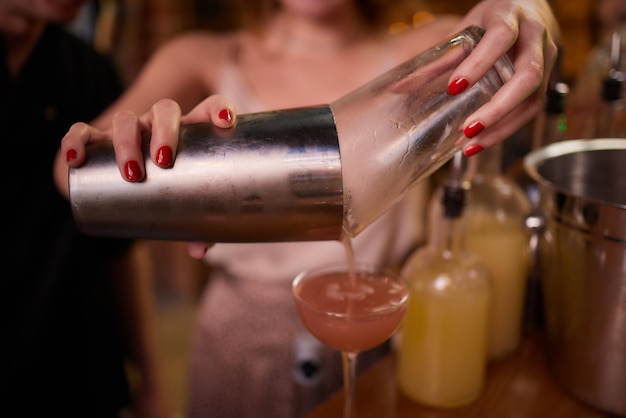 Barman derramando bebida alcoólica forte em copos pequenos em tiros de bar