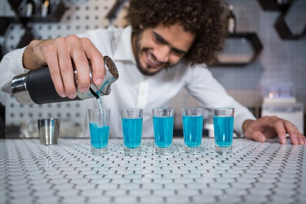 Foto barman, derramando coquetel em copos de shot