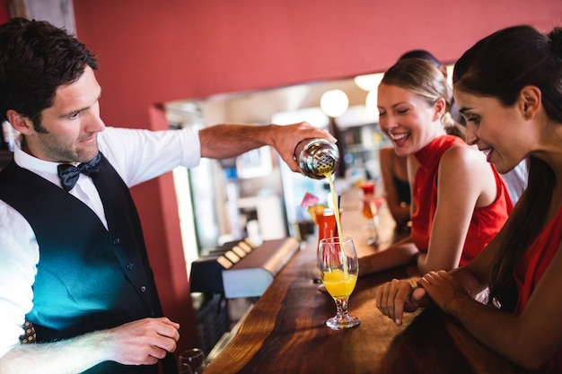 Barman, derramando coquetel em vidro no balcão de bar