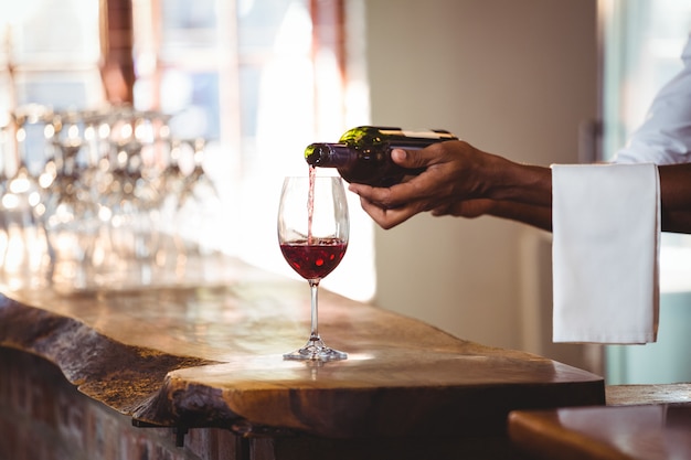 Barman, derramando vinho tinto em um copo