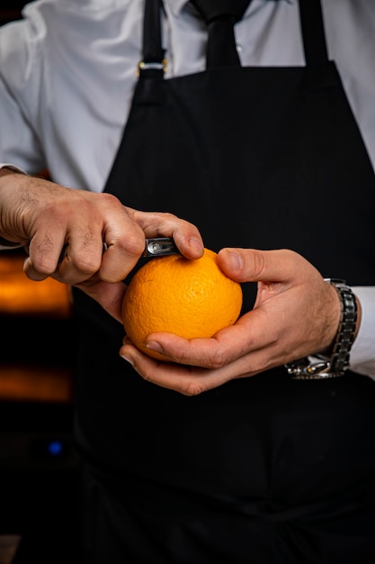 Barman descascando uma laranja