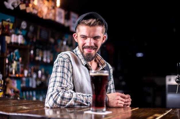 Barman encantador servindo bebida alcoólica fresca nos copos na boate