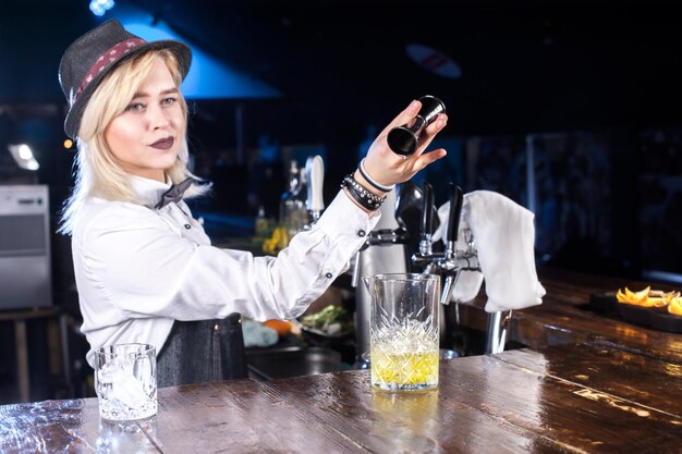 Barman especialista mulher derramando bebida alcoólica fresca nos copos no bar