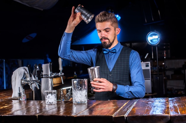 Barman especialista servindo bebida alcoólica fresca nos copos na boate