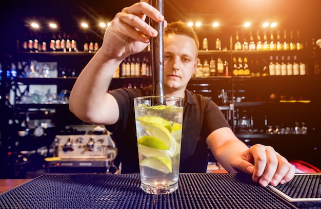 Barman está fazendo um coquetel no balcão do bar. Coquetéis frescos. Barman no trabalho. Restaurante. Vida noturna.