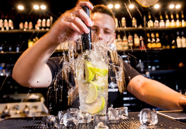 Barman está fazendo um coquetel no balcão do bar. coquetéis frescos. barman no trabalho.